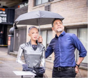 Sophia the Robot and Dr. David Hanson posing under an umbrella