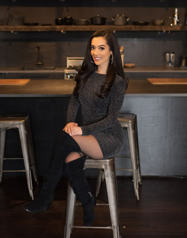 Hala Taha sitting on stool in a black dress