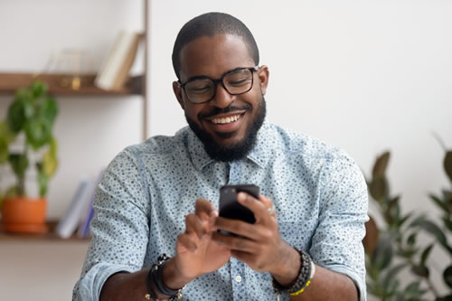 smiling african-american texting on his mobile phone