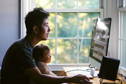 father and child sitting at home office desk and computer