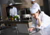woman chef on laptop in restaurant kitchen