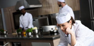 Food for Thought: The Parallels Between Chefs, Security and Tech woman chef on laptop in restaurant kitchen