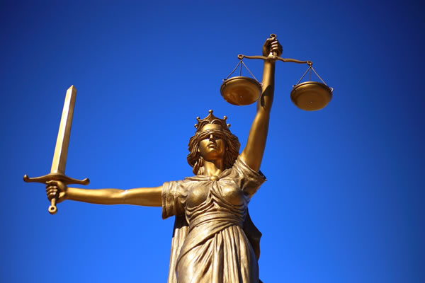 bronze statue of Lady Justice with blue sky background