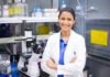 How Learning and Persistence is Changing Clinical Trials for Better Smiling woman scientist in lab with arms crossed looking at camera