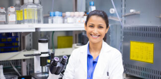 Smiling woman scientist in lab with arms crossed looking at camera