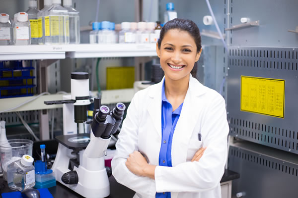 Smiling woman scientist in lab with arms crossed looking at camera