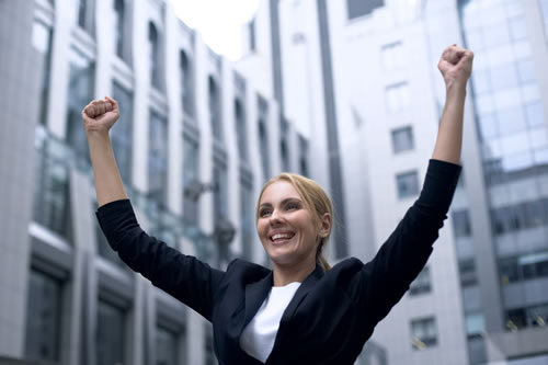 woman in business suit celebrating with hands in air