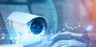 How Blockchain Can Help Us Build a World that’s Both Safe and Connected image of surveillance camera with human hands typing on laptop