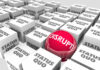 How Tech Innovators Continue to Find New Ways of Disrupting Old Models colorful shiny red sphere with word disrupt, showing tech innovation amidst drab white boxes with status quo