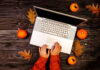 Surviving A COVID Thanksgiving top view of girl typing on laptop with autumn leaves and pumpkins around