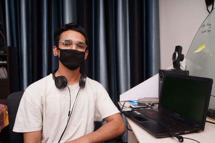 developer at work desk with mask on looking at camera
