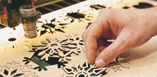 What Are Laser Cutters and How Do They Work? man cutting out snowflakes on poster board with laser cutter