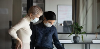 two executive women working in office with masks on