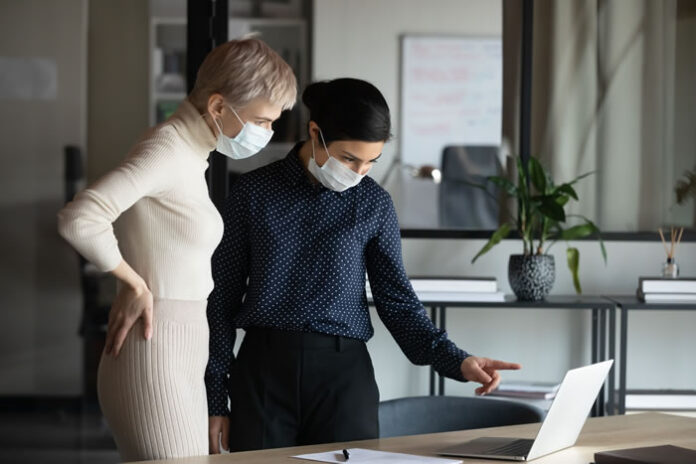 two executive women working in office with masks on