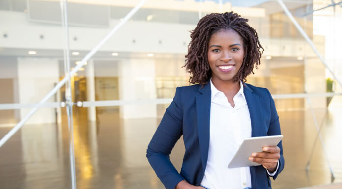 black women business leader holding ipad and smiling into camera