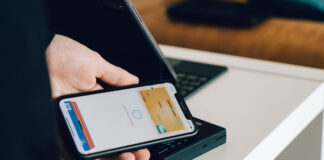 Global Growth Requires Local Payment Capabilities young man using mobile phone to pay retailer electronically with local payment capabilities