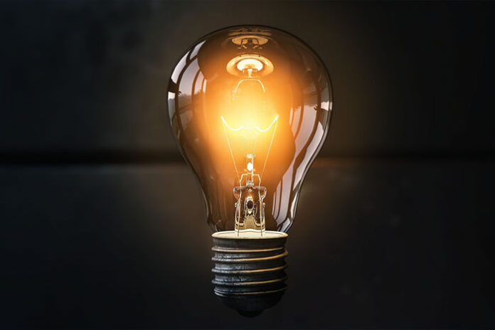 picture of a yellowish light bulb lit up in a dark room