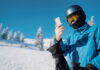 young skier looking at his cell phone after a run down the snow slope