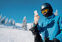 young skier looking at his cell phone after a run down the snow slope