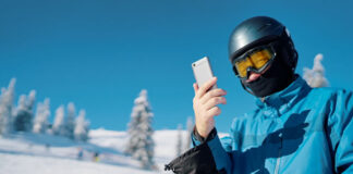How Measurable Data is Enabling Skiers to Level Up young skier looking at his cell phone after a run down the snow slope