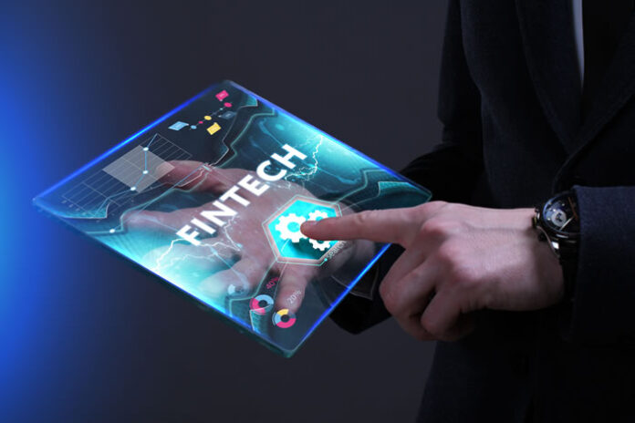 man holding digital virtual tablet and selecting FinTech