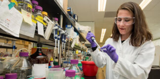 How AI Helps Solve the Challenges Facing SMB Pharmaceutical Companies woman pharmacist working with vials in tech