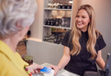 Top Tech Tips to Jumpstart Your Hair Stylist Career older woman using tech to pay for service at salon with younger attendee girl smiling