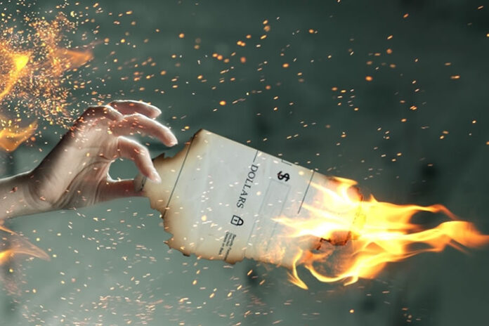 woman holding a paper that is on fire signifying the cost of paper