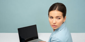 girl typing on her business laptop while suspiciously looking over her shoulder