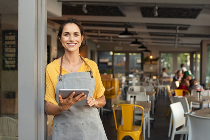 smiling restaurant owner with tablet using smart tech innovation