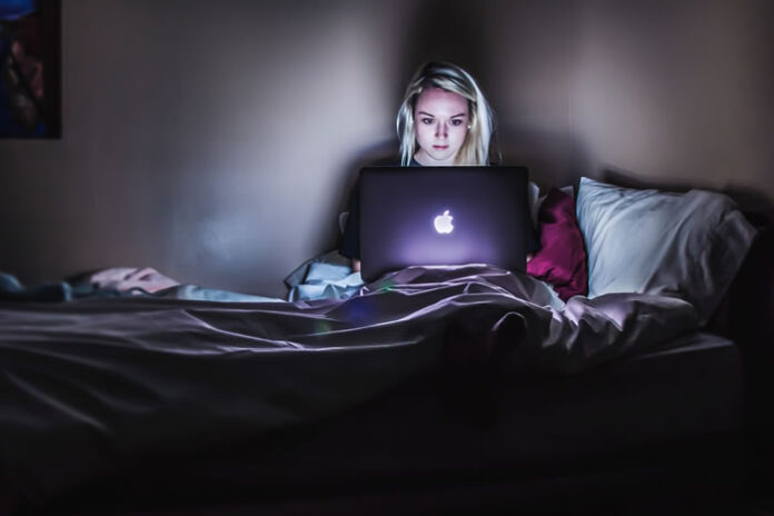 girl working on laptop from her bed as part of the work-life balance conundrum