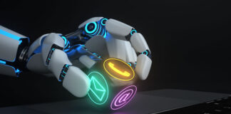 robot hand holding an electronic dice piece in front of keyboard