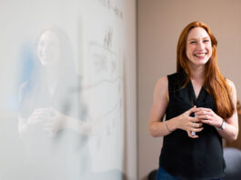 smiling woman solving a problem at a white board