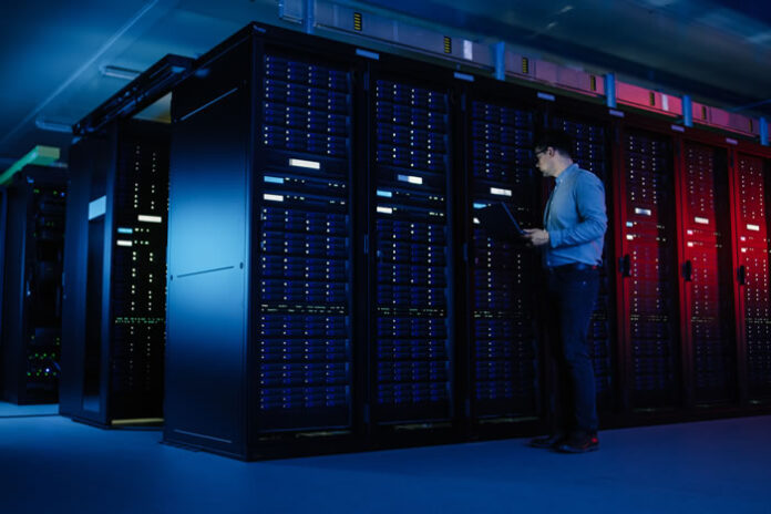 engineer inspecting rows of server cabinets in the cloud