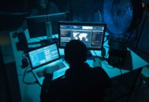 hacker sitting in dark room at his computers