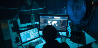 hacker sitting in dark room at his computers