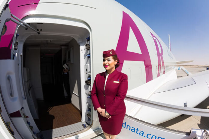 stewardess in company uniform standing in front of airplane door