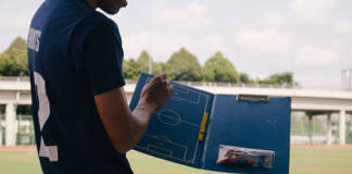 The Easiest Path to Effective Brand Positioning in 2022 soccer coach displaying play field on notebook to his team