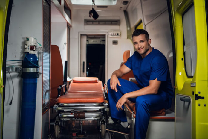 smiling EMS personnel sitting in medical ambulance