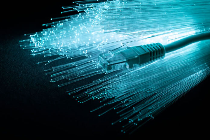 fiber optic strands with Ethernet network cable in blue light