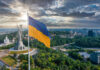 The War Between Russia and Ukraine is Affecting Staff Augmentation Ukraine flag flying in Kyiv over a city of businesses and staffing