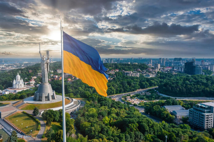 Ukraine flag flying in Kyiv over a city of businesses and staffing
