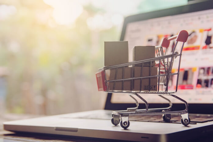 picture of a miniature shopping cart sitting on a laptop representing the online marketplace