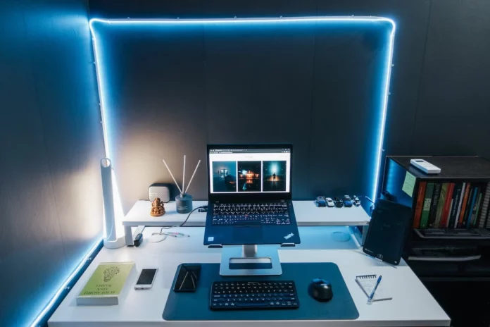 A Computer Set on a White Table with Blue LED Lights on Background Near a Set of Books