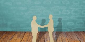 The Risks and Rewards of Acquiring a Competitor: An Analysis acquiring a competitor with two businessmen shaking hands