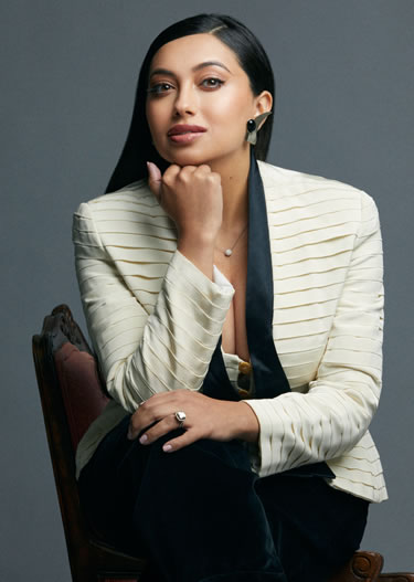 Shama Hyder in white blazer and resting chin on her fist