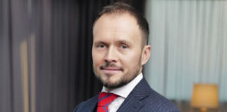 Bartosz Skwarczek Feature Bartosz Skwarczek headshot - standing in blue suit and red tie