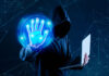 Heightened Cyber Threats Expected in Winter 2024 hacker with laptop holding up hand to launch cyber threats