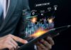 Looking Ahead to 2024 – How Can We Prepare Our Finances? man using a tablet with a holographic finance dashboard and how we prepare our finances