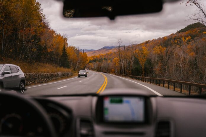 Car riding on highway through autumn forest